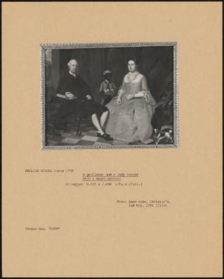 A Gentleman And A Lady Seated With A Black Servant