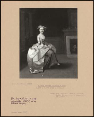 A Lady Seated Holding A Book