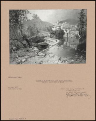 A View Of A Water Mill In A Hilly Landscape