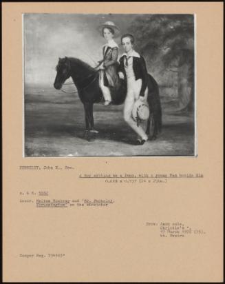 A Boy Sitting On A Pony, With A Young Man Beside Him